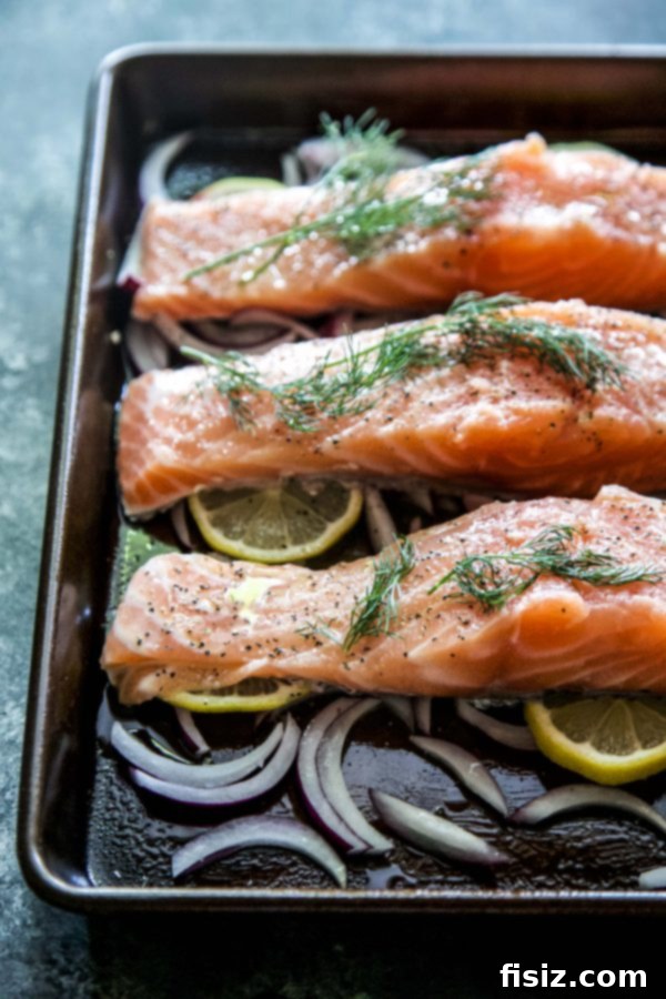 Preparing the baking dish with lemon and red onion slices for Greek Baked Salmon