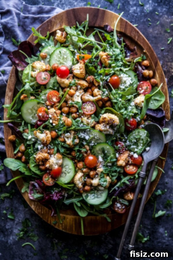 A beautifully presented Smoky Cauliflower Chickpea Salad, featuring golden roasted cauliflower and chickpeas on a bed of fresh mixed greens, drizzled with honey Dijon vinaigrette.