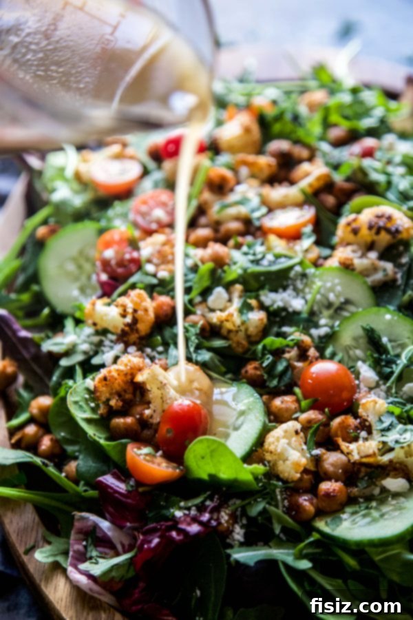 The Smoky Cauliflower Chickpea Salad fully assembled in a bowl, drizzled generously with the honey Dijon vinaigrette, ready to be served.