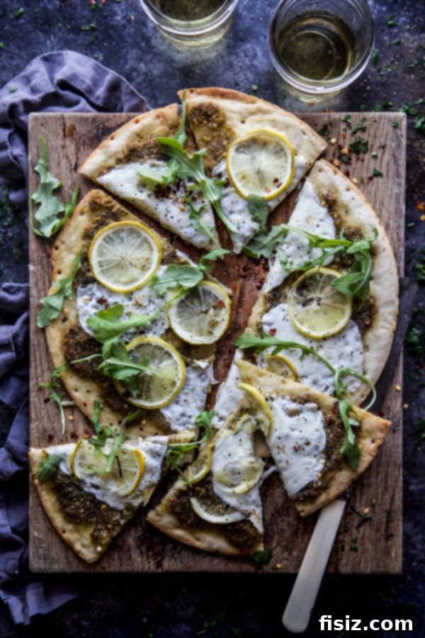 A freshly baked Arugula and Meyer Lemon Pizza, still warm, with bright green arugula and golden lemon slices on top of a cauliflower crust.