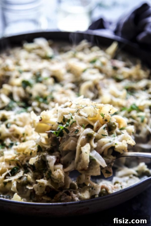 Rustic Tuscan Tuna Bake 5 A spoon scooping a generous portion of Tuscan Tuna Casserole from the skillet.