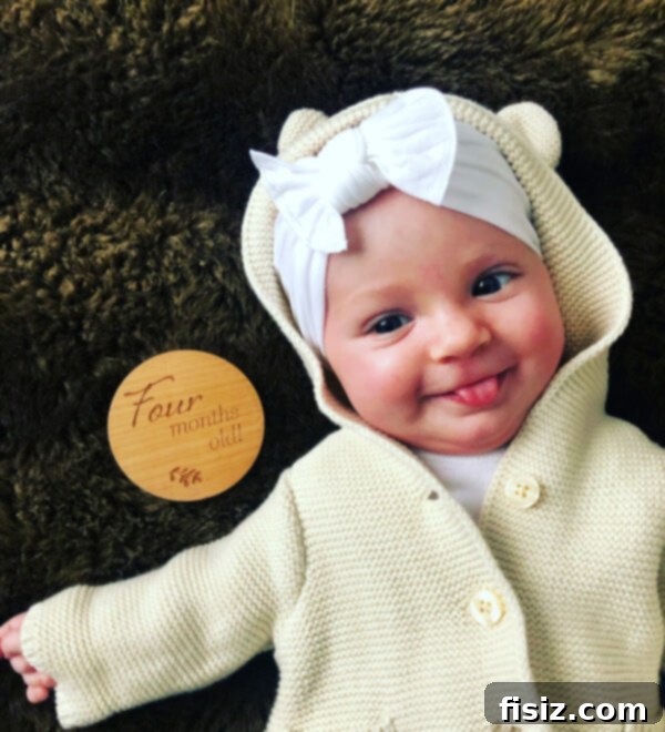 Four Months with Charlie 2 Smiling baby Charlie in a white onesie looking at the camera, capturing her fourth-month joy