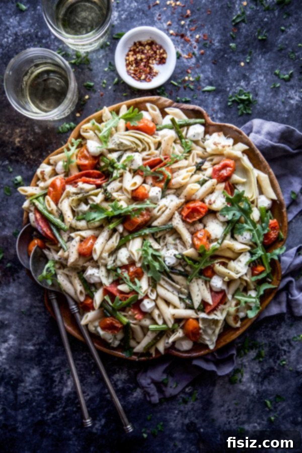 Vibrant Springtime Chickpea Pasta with Garden Vegetables 3 Close-up of roasted vegetables, including grape tomatoes, cauliflower, and asparagus, on a baking sheet.