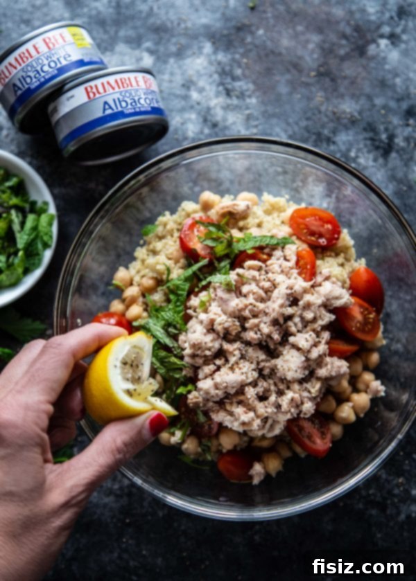 Sun-Drenched Tuna Quinoa Medley 5 Fresh lemon being squeezed over a bowl of Mediterranean Tuna and Quinoa Salad
