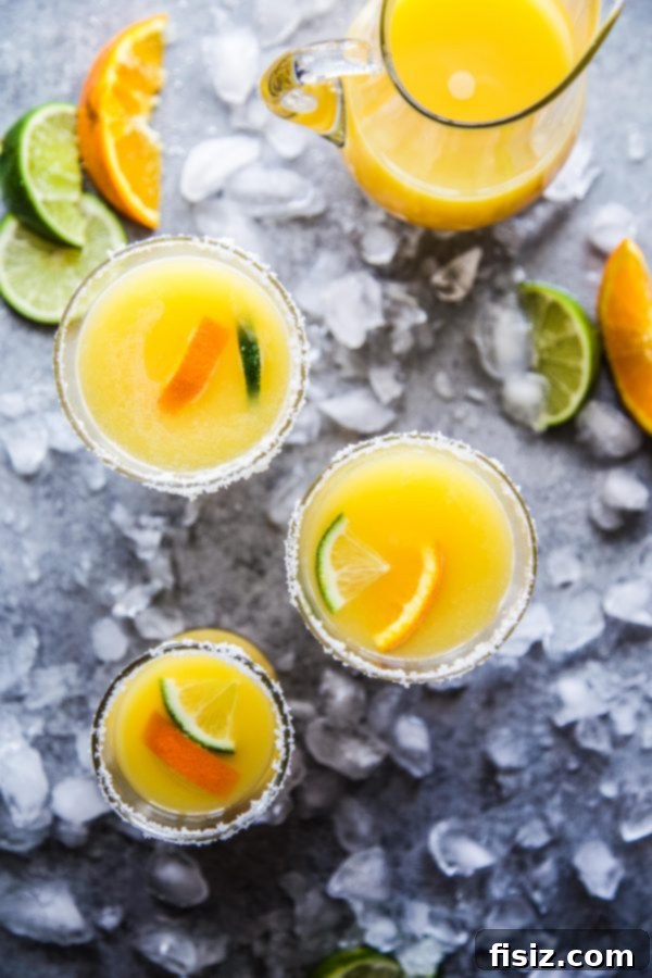 Sparkling Orange Tequila 3 Close-up of a Mimosa Margarita in a salt-rimmed glass with orange and lime slices.