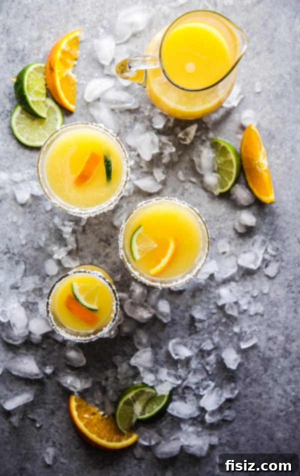 Sparkling Orange Tequila 6 A Mimosa Margarita cocktail in a glass with a lime wedge and salted rim.