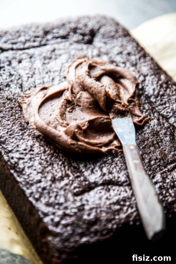 Decadent Double Chocolate Sheet Cake with Cream Cheese Frosting 4 A slice of chocolate sheet cake on a plate, revealing the thick layer of chocolate cream cheese frosting.