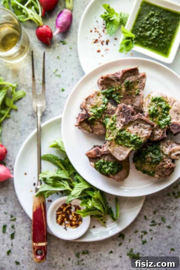Serving of grilled lamb loin chops with a spoonful of green salsa verde on top, ready to eat