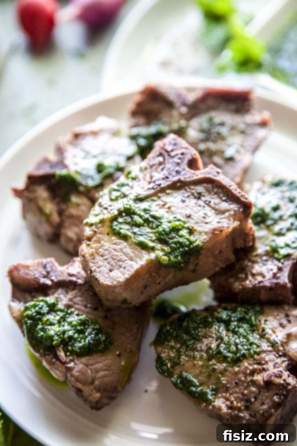 Plated grilled lamb loin chops with spinach salsa verde, garnished with fresh herbs