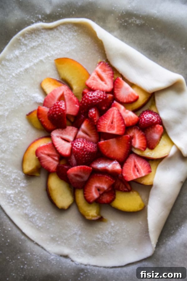 A close-up of a partially eaten Strawberry-Peach Galette slice with ice cream