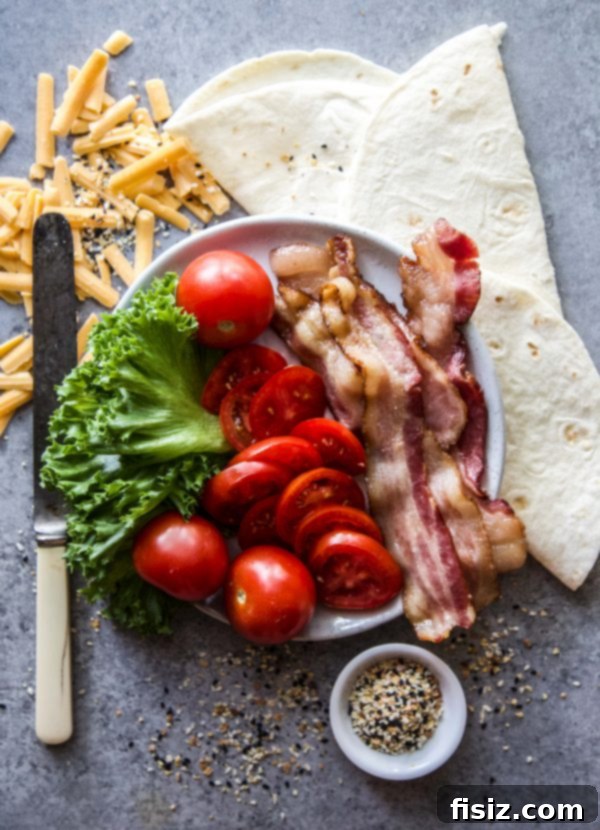 A prepared sheet pan with multiple uncooked Everything BLT Baked Quesadillas, brushed with oil and sprinkled with seasoning, ready for the oven.
