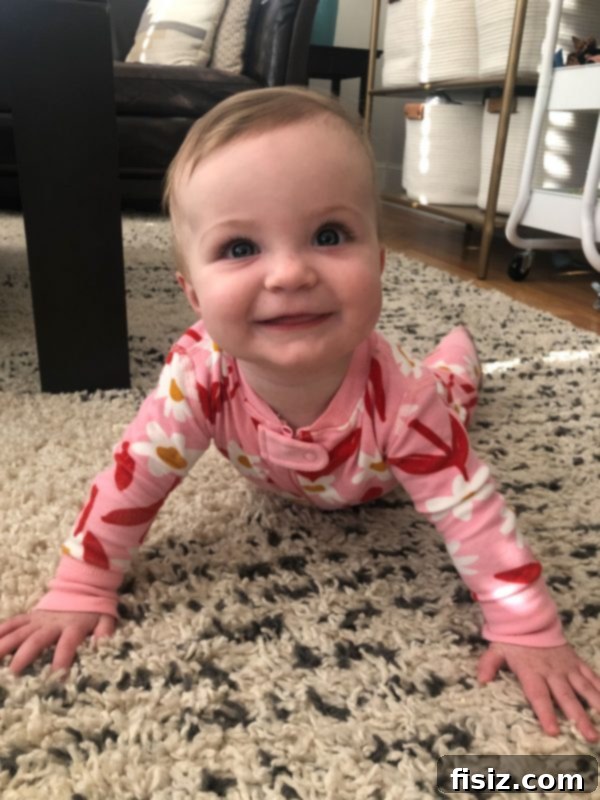 Nine Months of Life with Charlie 3 Charlie, a baby girl, smiling brightly while playing with a toy on a colorful playmat.