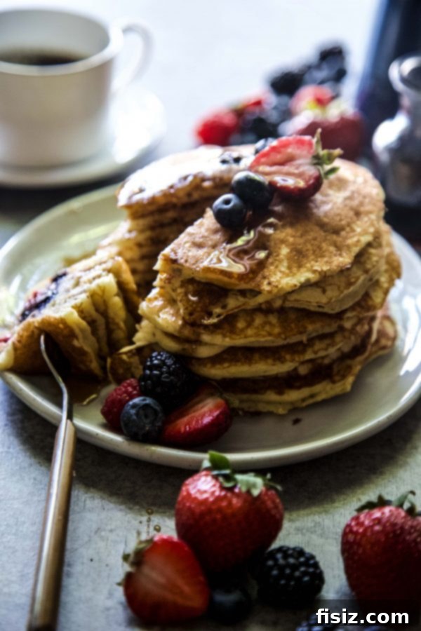 Almond Berry Bliss Stacks 5 Hand pouring pancake batter into a hot skillet with berries on top