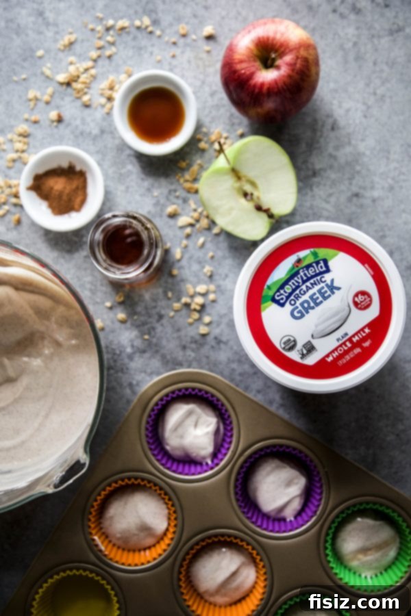 A tray of frozen apple cinnamon yogurt cups topped with granola and apple chunks, ready to be frozen.