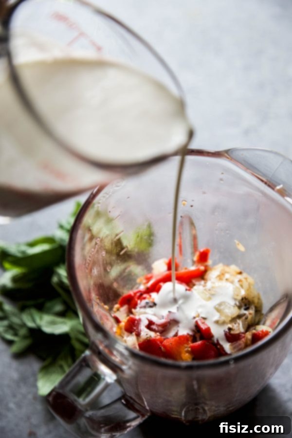 Indulgent Roasted Red Pepper Alfredo with Burst Tomatoes and Creamy Burrata 5 A serving of Roasted Red Pepper Alfredo with a fork, showing the texture of the sauce and pasta.