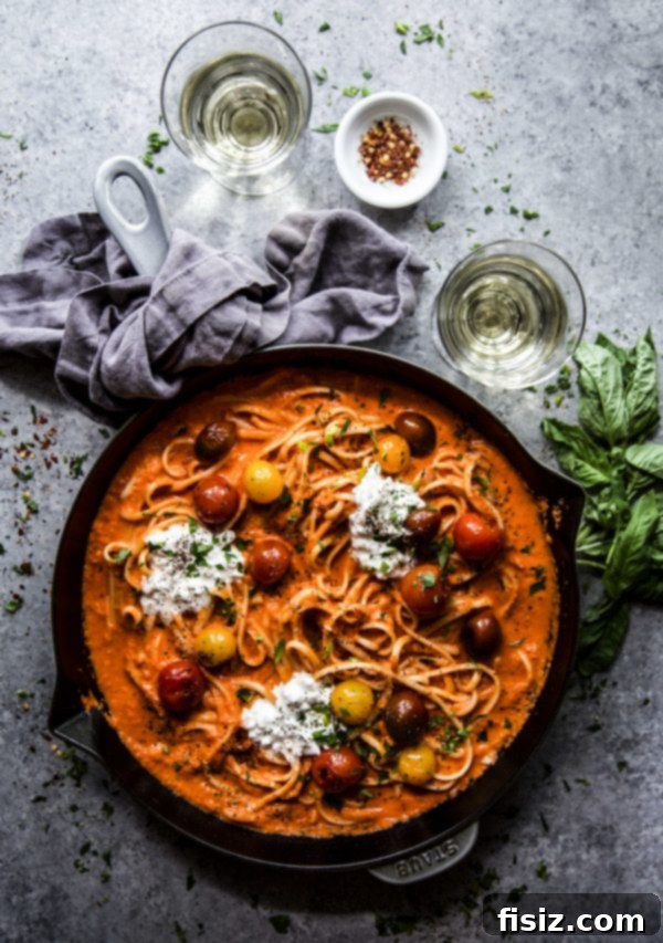 Indulgent Roasted Red Pepper Alfredo with Burst Tomatoes and Creamy Burrata 7 A bowl of Roasted Red Pepper Alfredo pasta, garnished with fresh basil and a drizzle of balsamic.