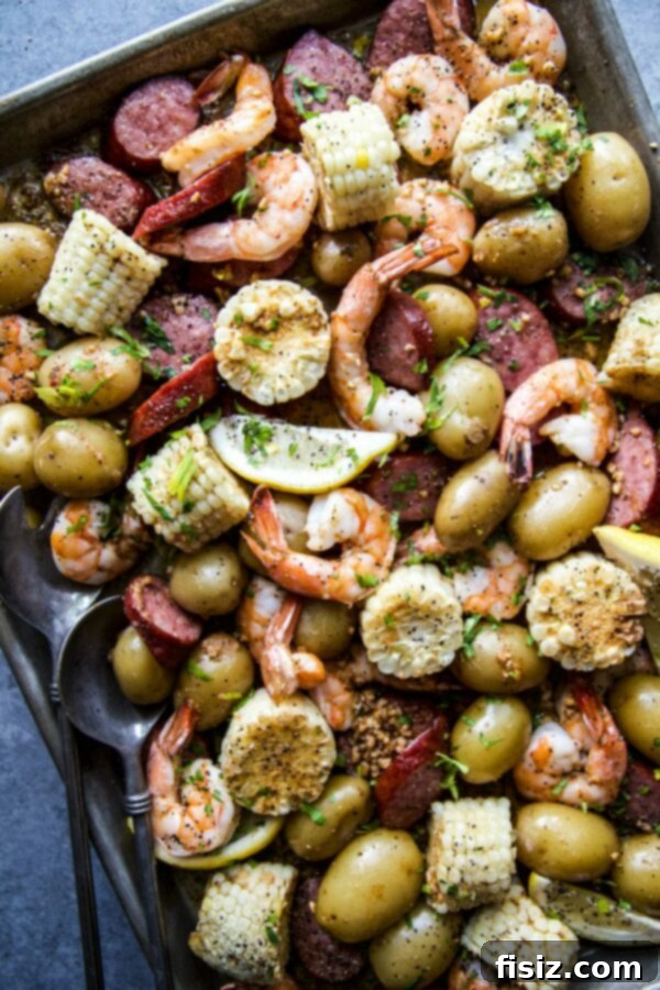 A close-up shot of a Sheet Pan Shrimp Boil, showing perfectly cooked shrimp, sliced sausage, and corn