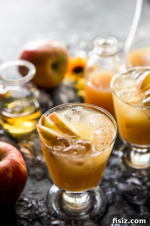 A refreshing Apple Bourbon Ginger Spritz cocktail garnished with apple slices, perfect for autumn