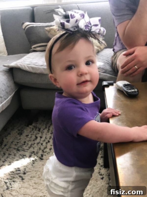 Month Eleven with Charlie 10 Baby Charlie dressed in a cute outfit, including a bow, celebrating a 'Wildcat Saturday', capturing a fun, spirited family tradition.