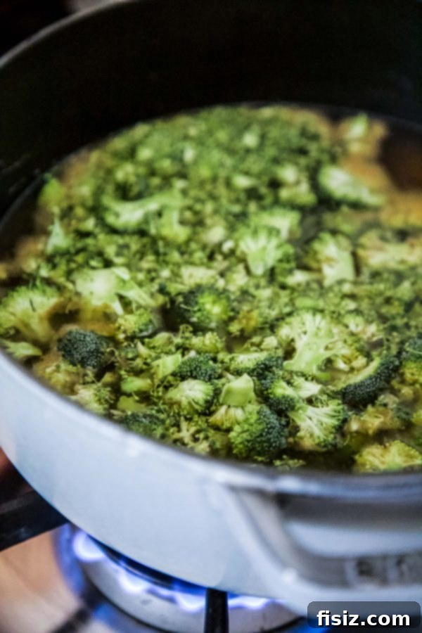 Creamy Smoked Gouda Broccoli Soup with Crispy Garlic Cheese Croutons 4 Ingredients for Smoked Gouda Broccoli Soup laid out on a cutting board, including fresh broccoli, Gouda cheese, onion, and garlic.