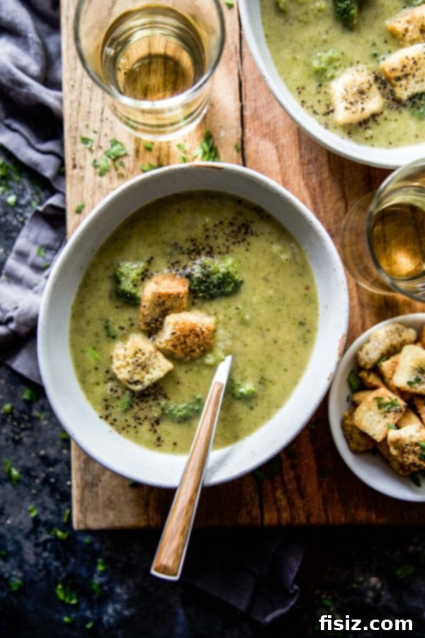 Creamy Smoked Gouda Broccoli Soup with Crispy Garlic Cheese Croutons 6 A bowl of Smoked Gouda Broccoli Soup on a wooden table, with fresh broccoli florets scattered around.