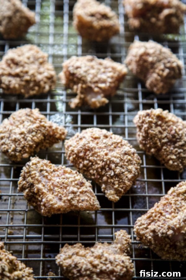 Spiced Pecan Chicken Bites & Chipotle Mustard Dip 5 Uncooked Spiced Pecan Chicken Nuggets arranged on a wire rack on a baking sheet, ready for the oven.