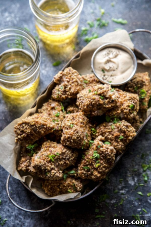 Spiced Pecan Chicken Bites & Chipotle Mustard Dip 7 Baked Spiced Pecan Chicken Nuggets served on a plate with Chipotle Mustard sauce and fresh parsley garnish.