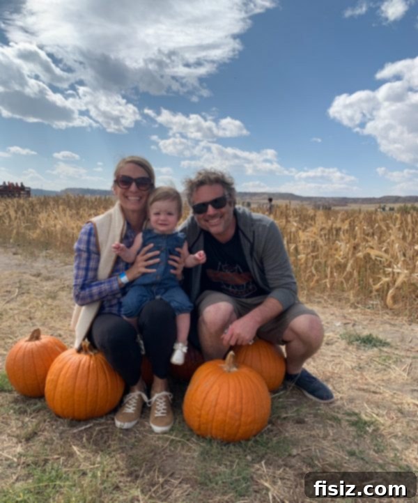 Our First Year with Charlie 15 Family photo at a pumpkin patch on a windy day, with pumpkins and hay bales around.