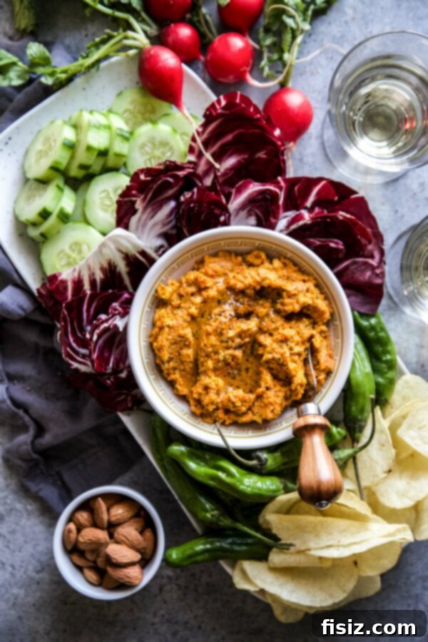 Smoky Roasted Carrot Spread 2 Creamy Smoky Carrot Dip in a rustic bowl, surrounded by fresh cucumber slices, pita bread, and vibrant radishes, perfect for a party appetizer
