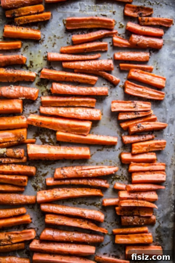 Smoky Roasted Carrot Spread 4 Freshly cut carrot strips seasoned with olive oil, salt, and pepper, spread on a baking sheet, ready for roasting to achieve perfect tenderness and sweetness.