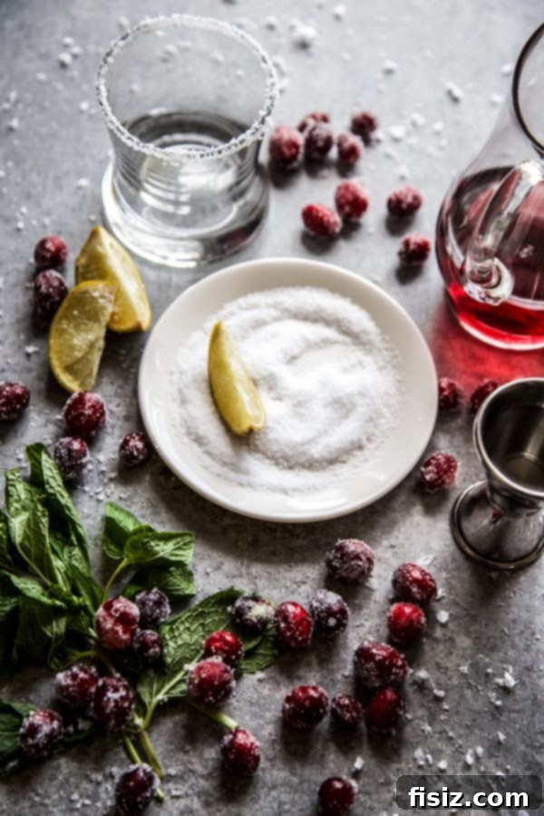 Mistletoe Kiss Margaritas 4 Ingredients for a cranberry margarita laid out on a board, including cranberries, lime, tequila, and triple sec.