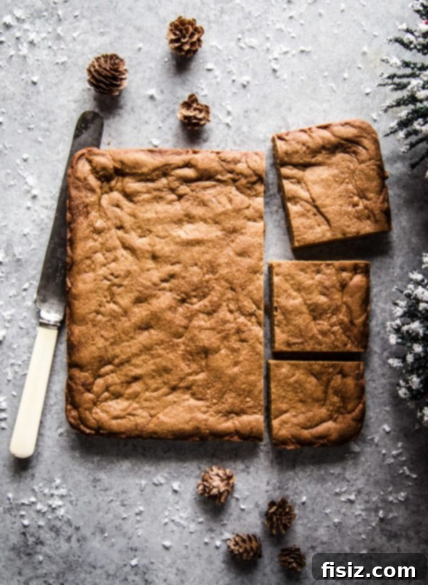 Golden Gingerbread Bars with Creamy Caramel Frosting 4 Freshly baked gingerbread cookie bars, still warm and golden brown, cooling in a baking pan on a table.