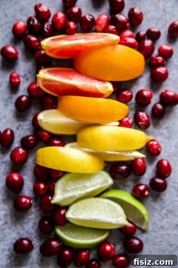 Ruby Red Whiskey Sour 4 Assortment of fresh citrus fruits including lemons, limes, and oranges, along with vibrant red cranberries on a wooden cutting board, essential ingredients for the cocktail.