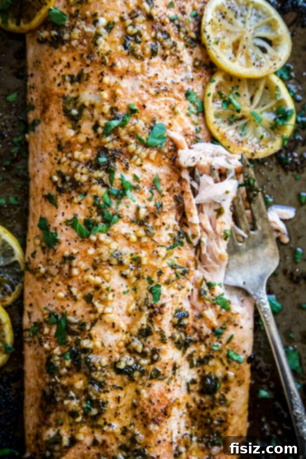 Spicy Cajun Salmon with Rich Garlic Parmesan Sauce 2 Baked cajun salmon on a sheet pan with a fork digging into the flaky fish.