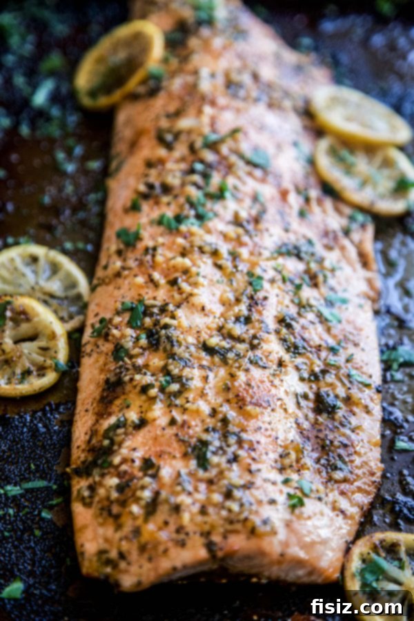 Spicy Cajun Salmon with Rich Garlic Parmesan Sauce 3 Baked salmon on a sheet pan, covered with spices and sliced lemon.