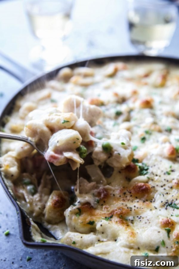 Gnocchi Chicken Pot Pie (Crustless) 7 A serving spoon scoops out a portion of crustless chicken pot pie topped with gnocchi, showing the creamy filling.