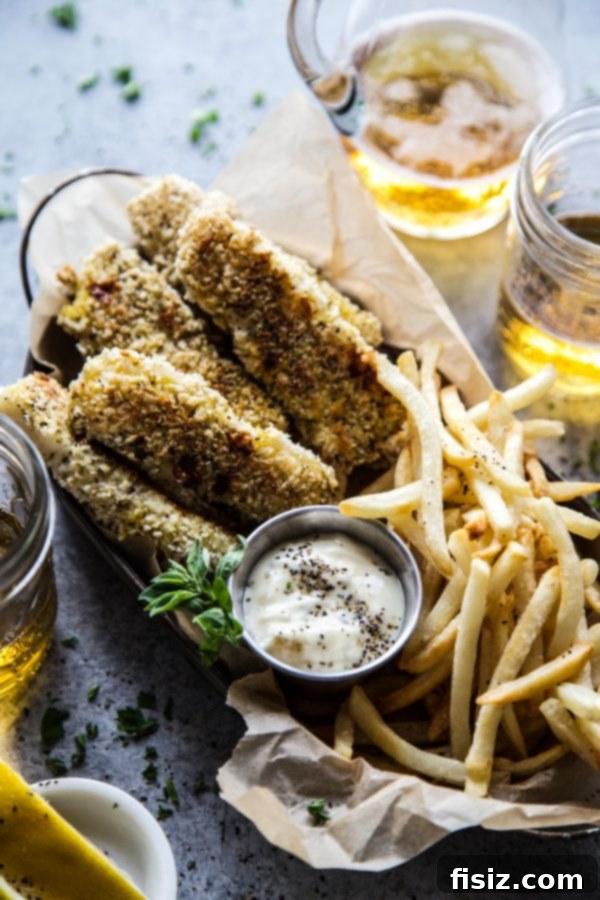 Zaatar Crusted Fish and Chips 6 A beautifully plated serving of Baked Za'atar Fish Sticks and Chips with tartar sauce and lemon, ready to be enjoyed.