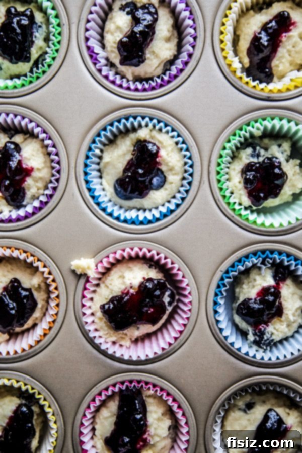 Double Blueberry Citrus Burst Muffins 5 Muffin batter with blueberries and blueberry preserve filling cupcake liners in a muffin pan