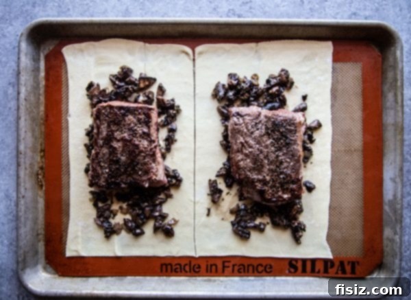 Lamb Wellington 4 Uncooked Lamb Wellington, expertly wrapped in puff pastry, resting on a baking sheet before baking
