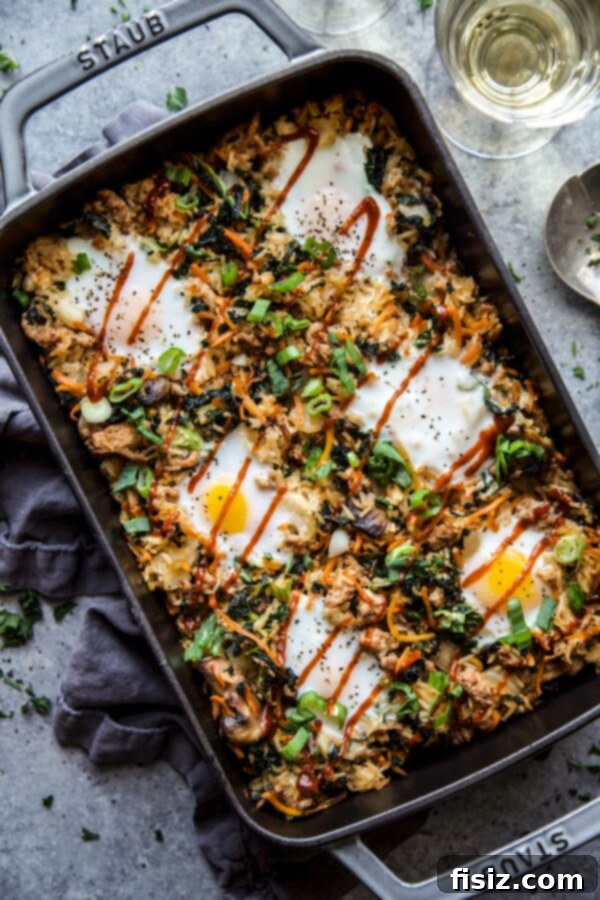 Vibrant Bibimbap Casserole with Ground Pork, garnished with fresh greens, served on a rustic wooden table