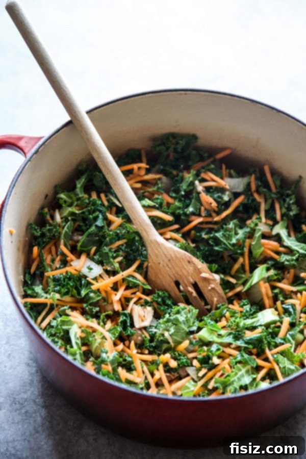 A colorful skillet full of mixed vegetables, including mushrooms, onions, garlic, kale, and carrots
