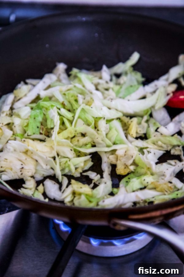 One-Pan Wonder Corned Beef Sliders 4 Close-up of shredded cabbage being sautéed in a hot skillet with butter.