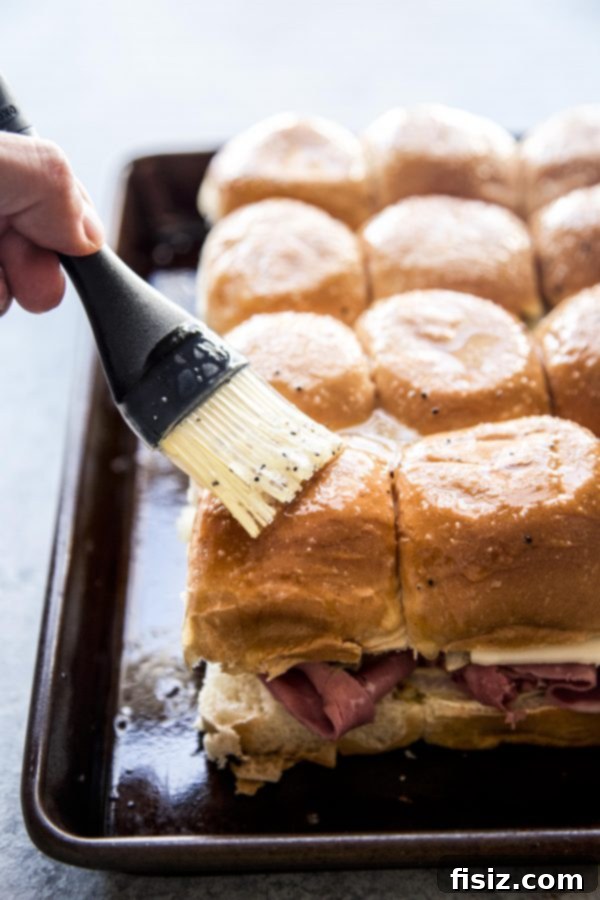 One-Pan Wonder Corned Beef Sliders 6 A pastry brush applies melted butter mixture onto the tops of corned beef sliders before baking.