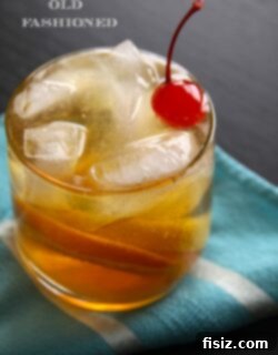The Art of the Old Fashioned 2 A beautifully styled Old Fashioned cocktail, garnished and ready, with a bottle of bourbon in the background.