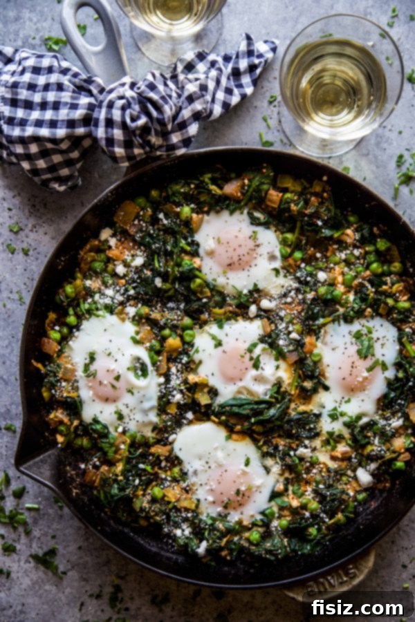 Green Shakshuka with Feta, Spinach, and Peas 7 Feta, Spinach, & Pea Shakshuka served in a skillet, with a spoon taking a portion