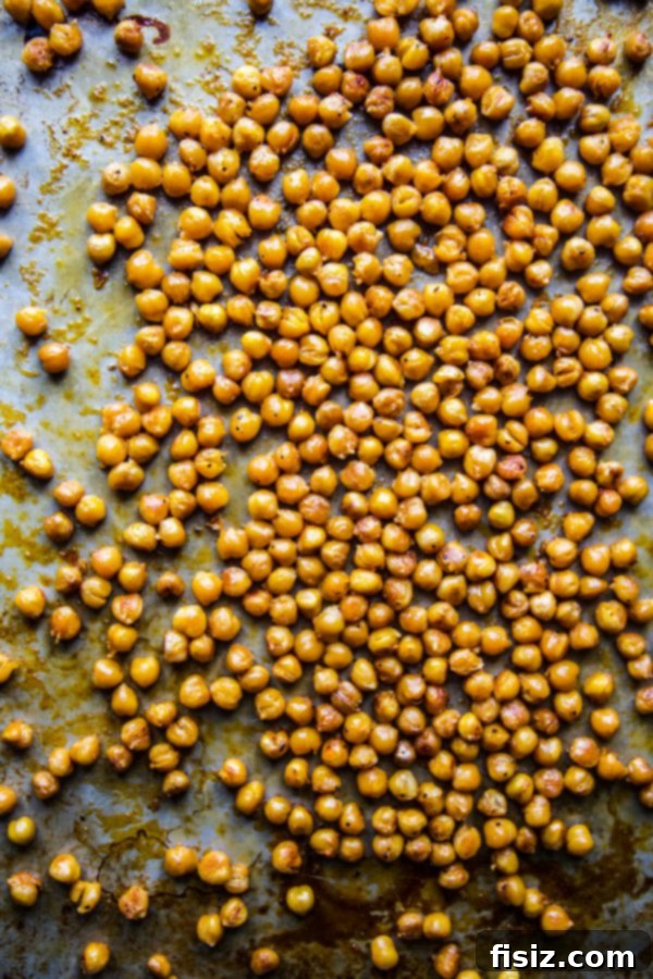 Zesty Chickpea Crunch 4 Crispy roasted chickpeas seasoned and ready for buffalo sauce on a baking sheet
