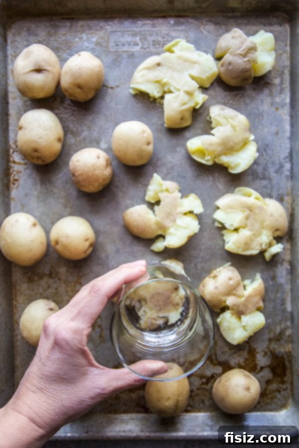 Southern Pimento Cheese Smashed Potatoes 5 Potatoes being smashed with the bottom of a glass
