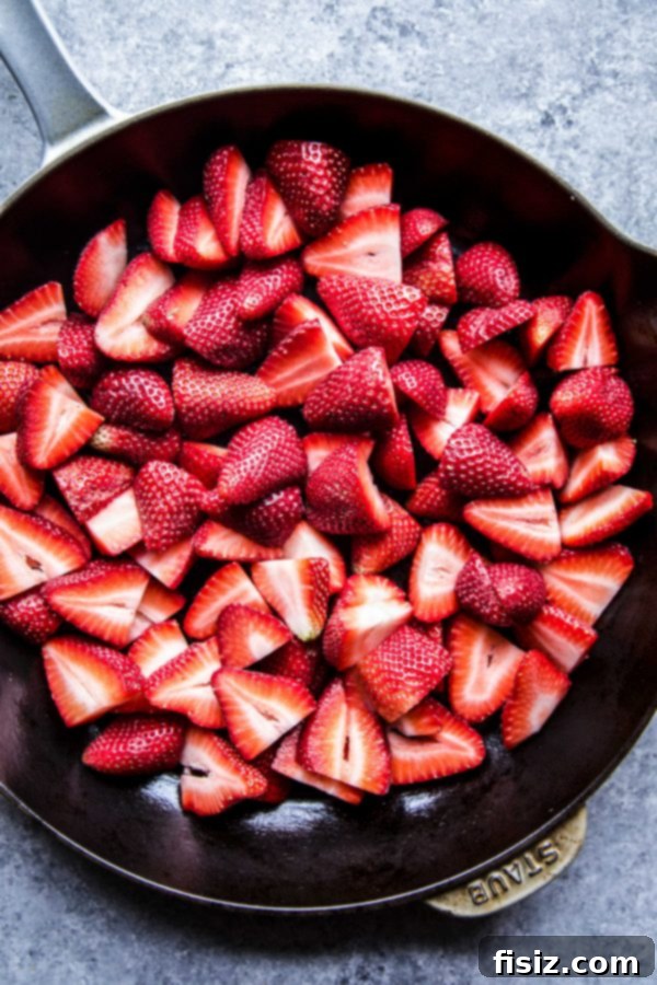 Fresh strawberries being prepared in a skillet for cobbler