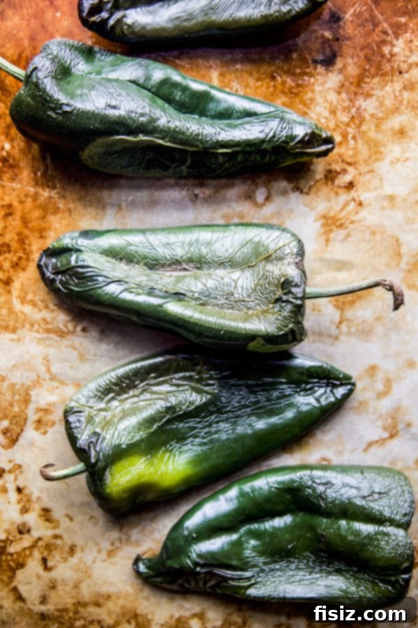 Effortless Chiles Rellenos 4 Fresh poblano chiles arranged on a baking sheet, ready for roasting.