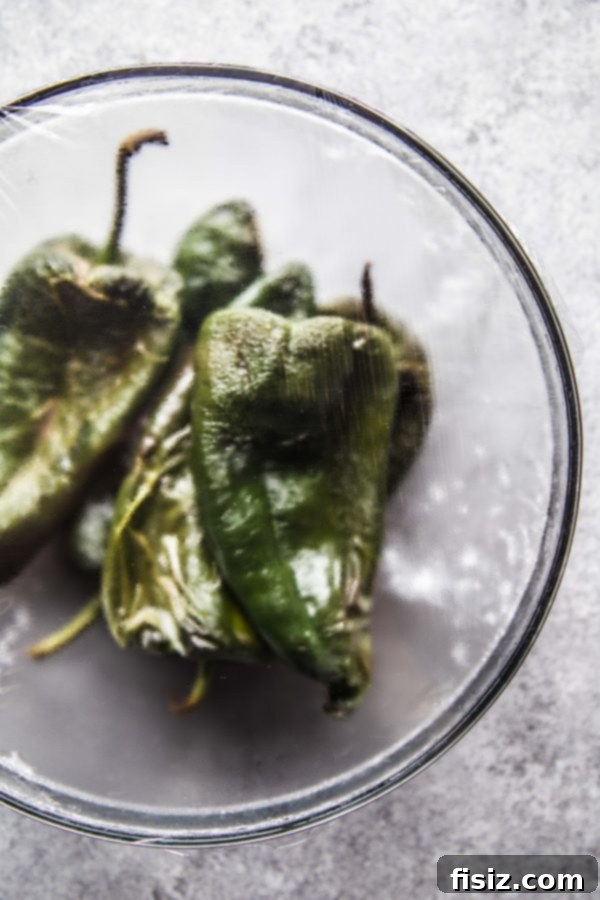 Effortless Chiles Rellenos 5 Steamed poblano chiles in a bowl, covered with plastic wrap, after roasting.